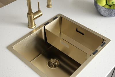 Overhead view of a brass sink and tap on a light worktop.