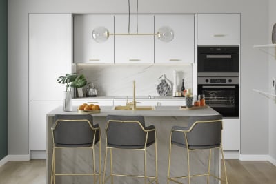 Nova Gloss White smooth slab surface cabinetry paired with light grey marbled worktop, splashbacks and brass details like tap, sink, chairs and lighting.