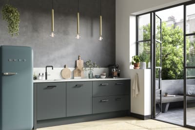 Soho kitchen in Arboretum Green with a blue Smeg fridge, white worktop and splashback matched with black handles and tap.