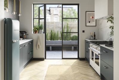 Soho kitchen in Arboretum Green with a blue Smeg fridge and glass doors to patio.