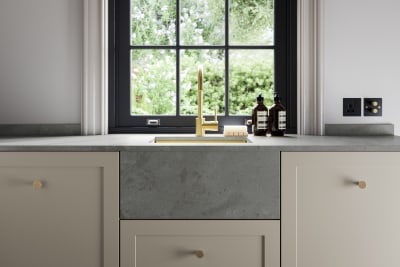 Close-up of brass tap and sink with marbled worktop with matching belfast sink, in Dunham kitchen from Magnet. Matched with brass handles.