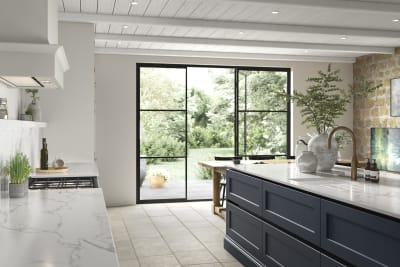 View of Integra Ludlow kitchen island in shade Midnight, with opened glass doors to a garden in the background.