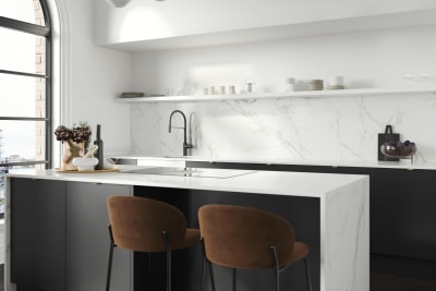 Bar stools at kitchen island, covered with marbled decor side in Magnet's minimal maximalism Hoxton kitchen in Sumi Black.