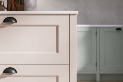 Closeup of Ludlow kitchen island, in a light pink colour with black accent handles.