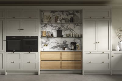 A neutral Shaker kitchen with Pebble and Nordic Craft cabinetry, marble splashback behind open shelves and paired with brass handles.