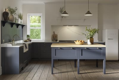 Open floorplan shaker kitchen in the dark blue shade Midnight, paired with a kitchen island and white Smeg fridge.