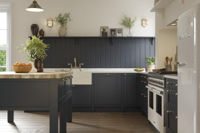 Open floorplan shaker kitchen in the dark blue shade Midnight, with a kitchen island and matching blue painted wood wall panel.