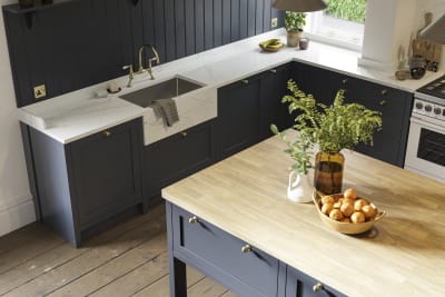 View of shaker kitchen in dark blue shade, with marble worktop and a kitchen island with light wood worktop.