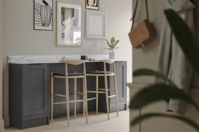 A dark grey Shaker bar sideboard with Charcoals cabinetry, paired with marble splashback and wooden high chairs.