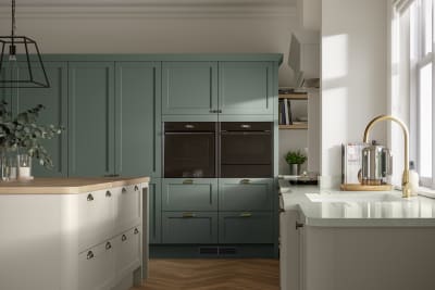 A contemporary kitchen with green and cream cabinets in Ambleside, featuring a Shaker-style design.