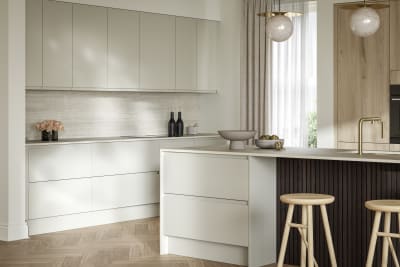 A bright and airy open-plan kitchen that incorporates Duxbury drawers and cabinets in Limestone, and Portobello units in Bosco. Combined with dark wood paneling on kitchen island bar.