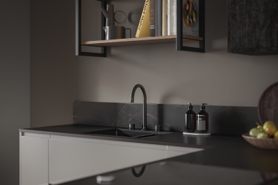 J-pull Duxbury kitchen cabinets in an elegant Fawn colour are matched with contemporary dark worktops and a black sink and tap.