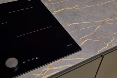 An organic marble-effect kitchen worktop, shown with modern Duxbury kitchen cabinets in Fawn, and black glass hob from SmartThings.