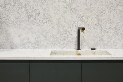 The Duxbury kitchen in rich green Arboretum, paired with white marble-effect worktops, built-in kitchen sink and a matte black and gold kitchen tap.