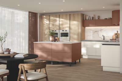 Modern frameless slab door with integrated handles, white cabinets paired with tall light wood Integra Portobello organic woodgrain cabinets and a kitchen island in the shade Baked Clay, Integra Soho from Magnet.