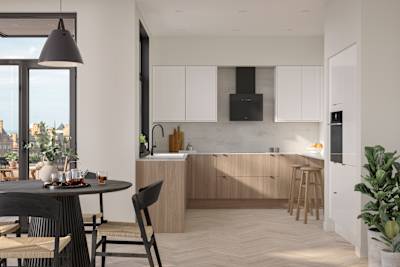 Open floorplan Ascoli kitchen from Magnet with Natural Oak cabinetry, a white worktop, Ascoli Gloss white wall cabinets over countertop and matching tall cabinets with a built-in oven all paired with small black handles, a black tap and black hood.