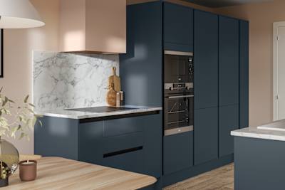 Handleless Integra Ascoli Mineral Blue, a dark blue kitchen with built-in ovens in tall cabinetry, an induction hob in white and grey marbled worktop with matching backsplash.