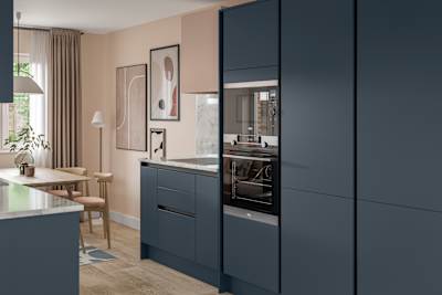 Handleless Integra Ascoli Mineral Blue, a dark blue kitchen with built-in ovens in tall cabinetry, an induction hob in white and grey marbled worktop with matching upstand.