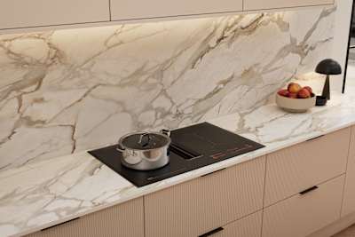 Fluted front kitchen Reed from Magnet in light warm neutral shade Shell, with a marbled splashback and worktop, induction hob and black handles