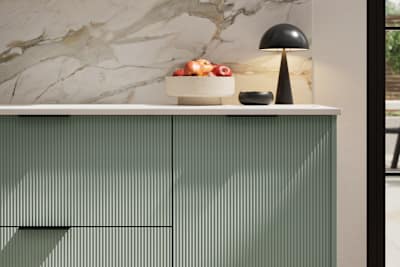 Fluted front kitchen Reed from Magnet in light green shade Eucalyptus Green, with a marbled splashback and black handles, herringbone wood flooring.
