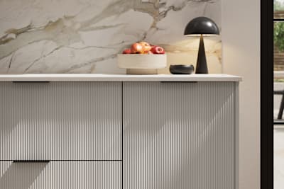 Fluted front kitchen Reed from Magnet in soft grey shade Dove Grey, with a marbled splashback and black handles, herringbone wood flooring.