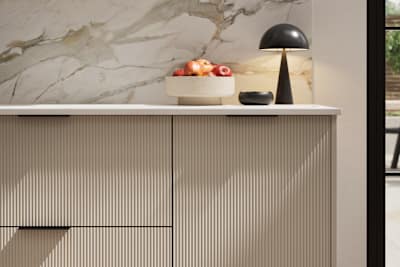 Fluted front kitchen Reed from Magnet in neutral shade Pebble Path, with a marbled splashback and black handles, herringbone wood flooring.
