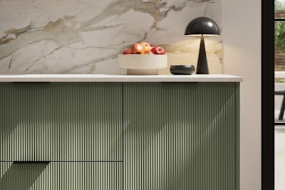 Fluted front kitchen Reed from Magnet in rich dark green shade Thyme, with a marbled splashback and black handles, herringbone wood flooring.