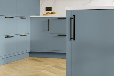 Modern slab front Soho Portland Blue kitchen with black handles, white marbled worktop and matching backsplash, wooden herringbone parquet flooring.