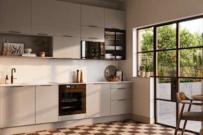 Angled view of modern slab front Soho Cornish Clay kitchen from Magnet in Pantone’s colour of the year ‘Mocha Mousse’ with bronze trim handles, handles, silestone quartz worktop and matching backsplash, checkered flooring.