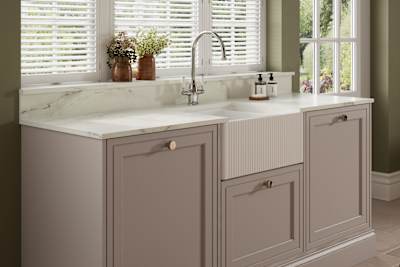 Shaker style painted wood grain cabinets Bewdley in the shade Cornish Clay with a marbled worktop and matching upstand, striped belfast sink with ceramic handle stainless steel tap.