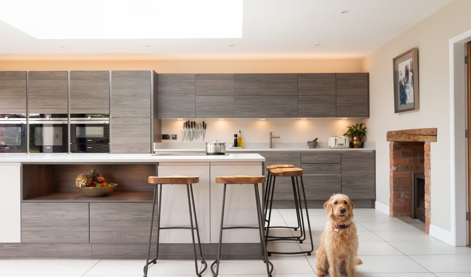 Straight view of the kitchen, with the family's dog sitting next to the kitchen island bar seats.