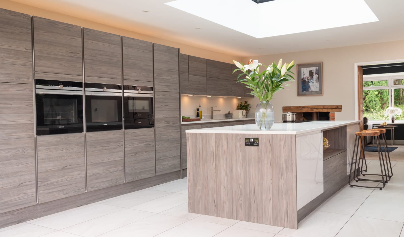 Angled view of Italian-inspired kitchen with an island decprated with a large vase of white lillies.