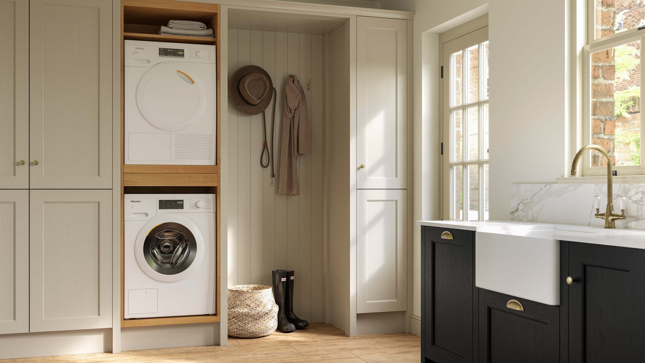 Utility room with Traditional Shaker-style tactile woodgrain Ludlow French Clay cabinets, washing machine and tumble dryer, Ludlow Sumi Black kitchen with brass accessories, Amtico oak stripwood vinyl flooring.