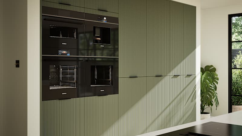 Green fluted kitchen fronts on tall cabinets with built-in appliances and black handles.