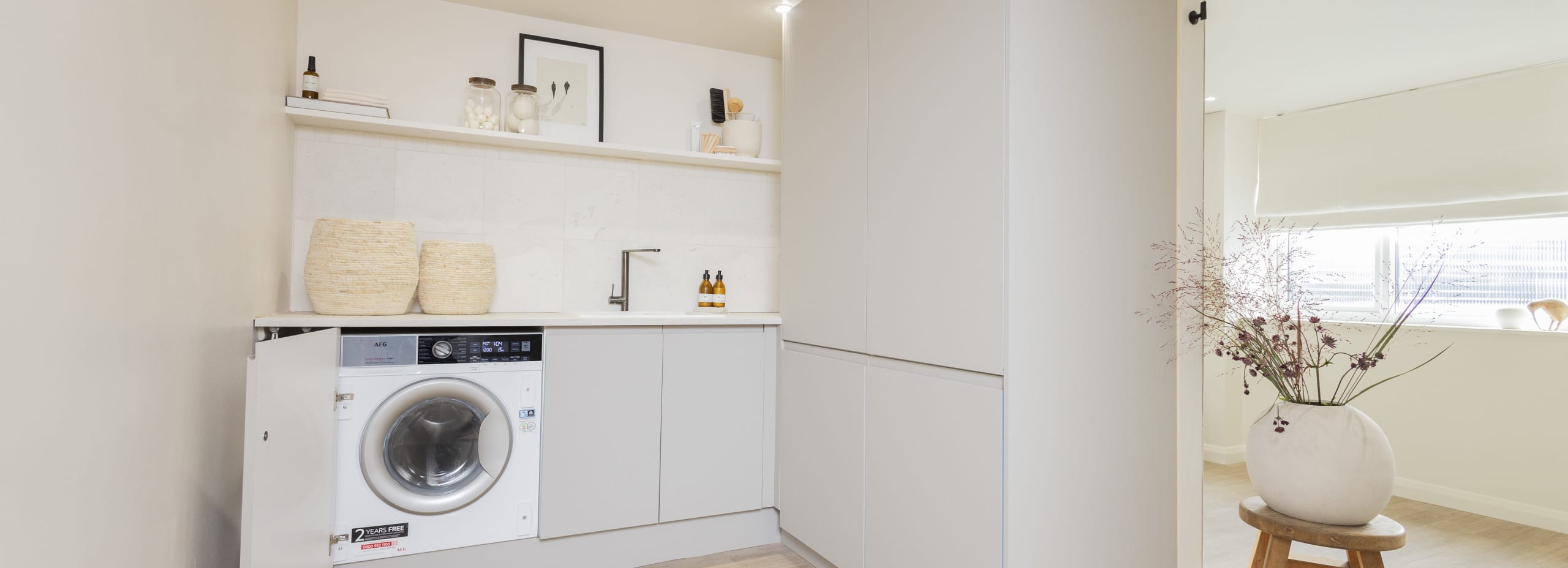 A utility room with cabinets with beige slab fronts