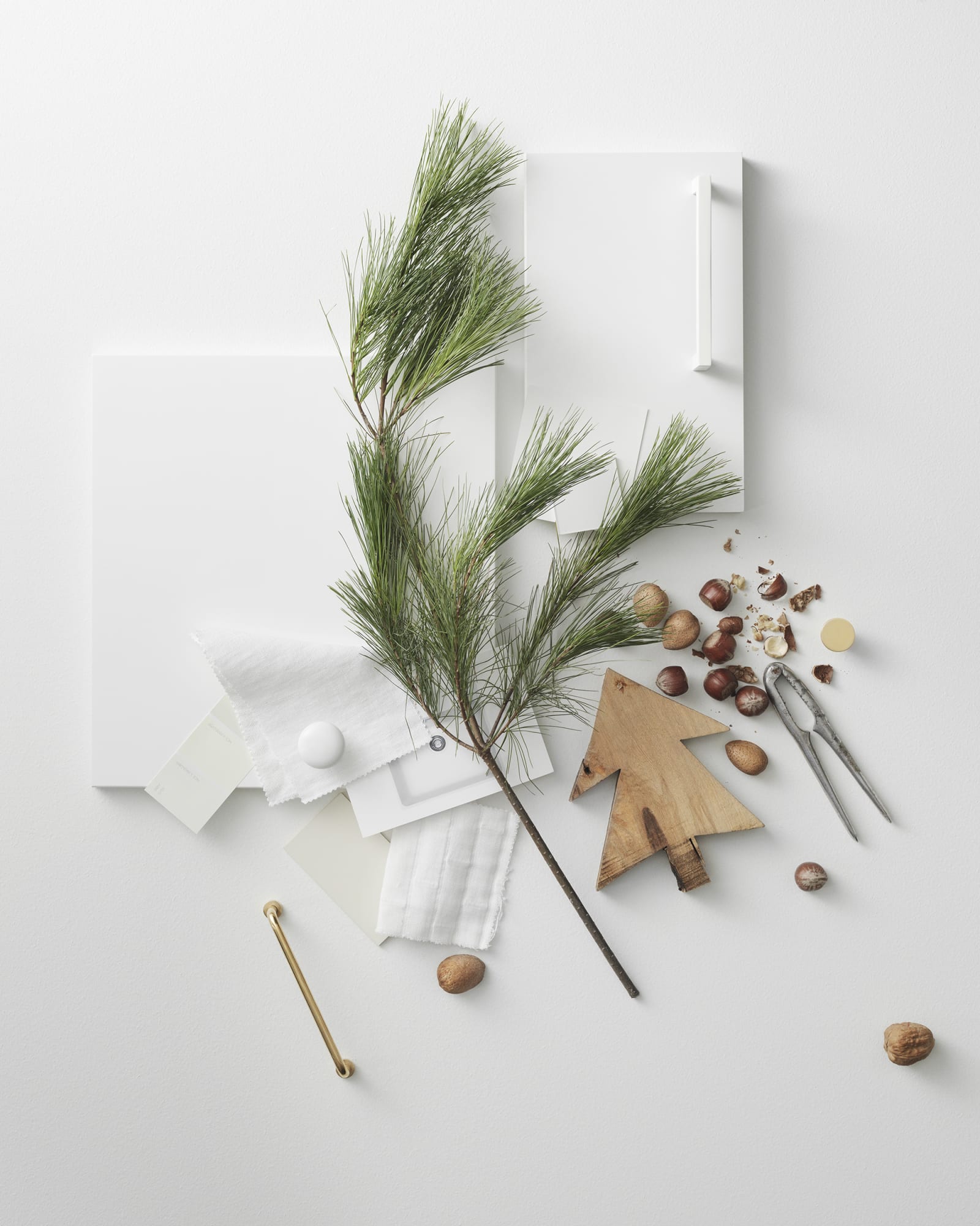 Moodboard med vit skåpslucka, vitt handtag, en gren med barr, trädetaljer