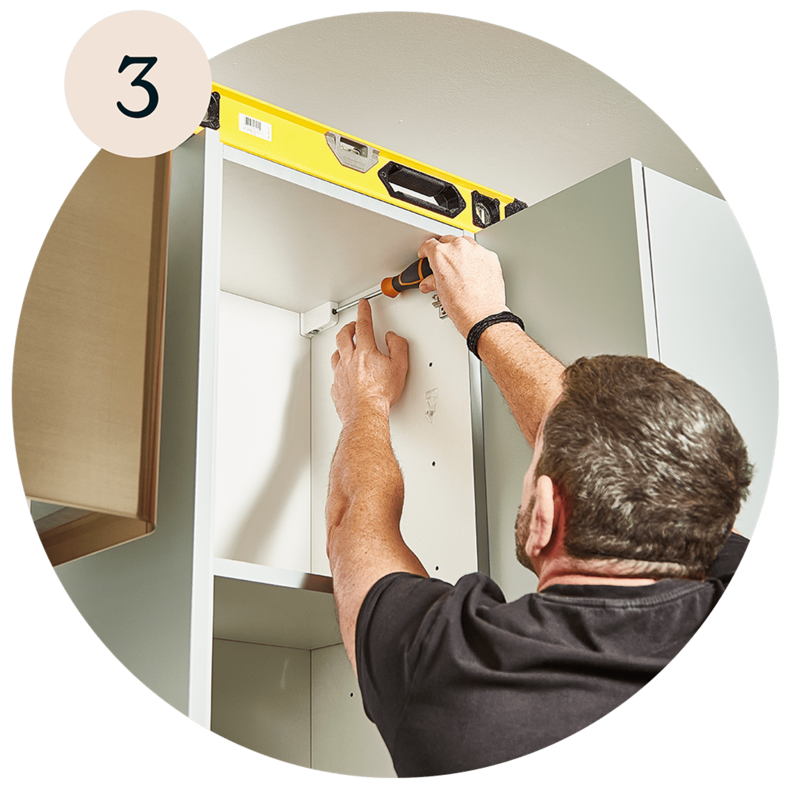 A man using tools to install a cabinet