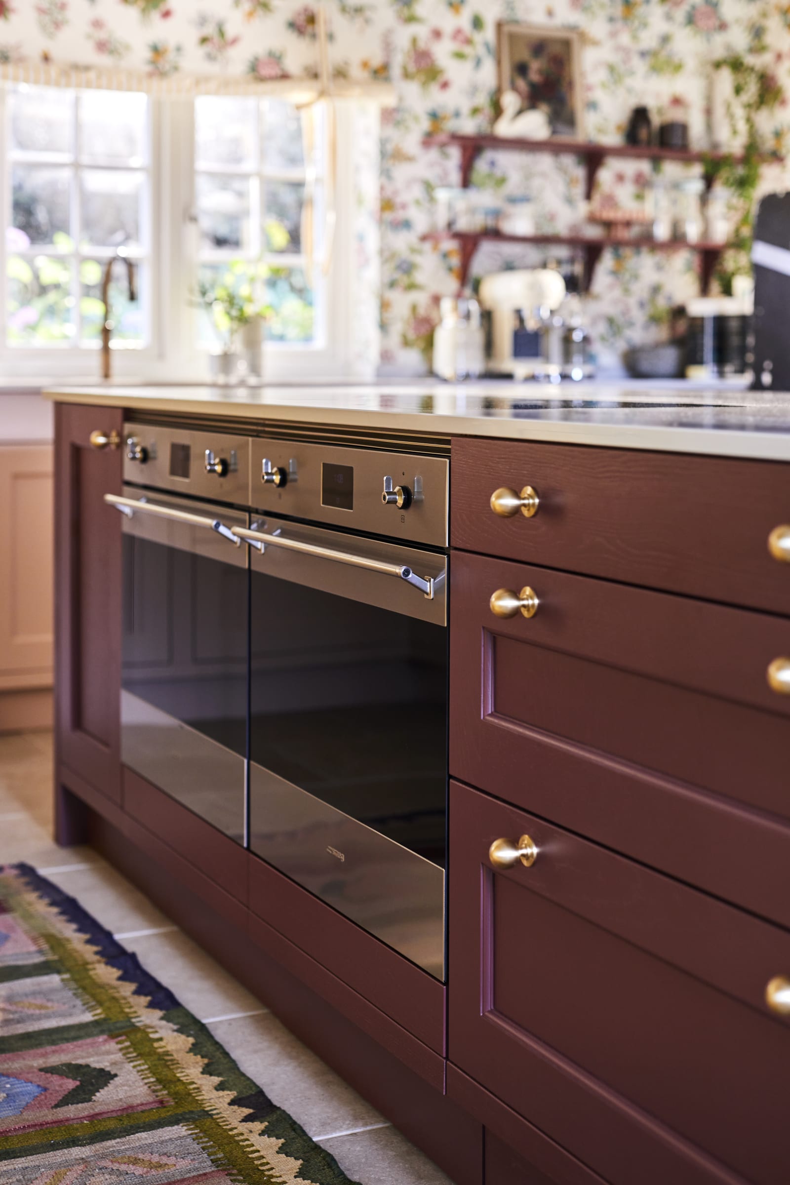 Parallell view of Sophie Robinson's maximalist kitchen, two Smeg ovens integrated into the Ludlow Burlington red kitchen island from Magnet.