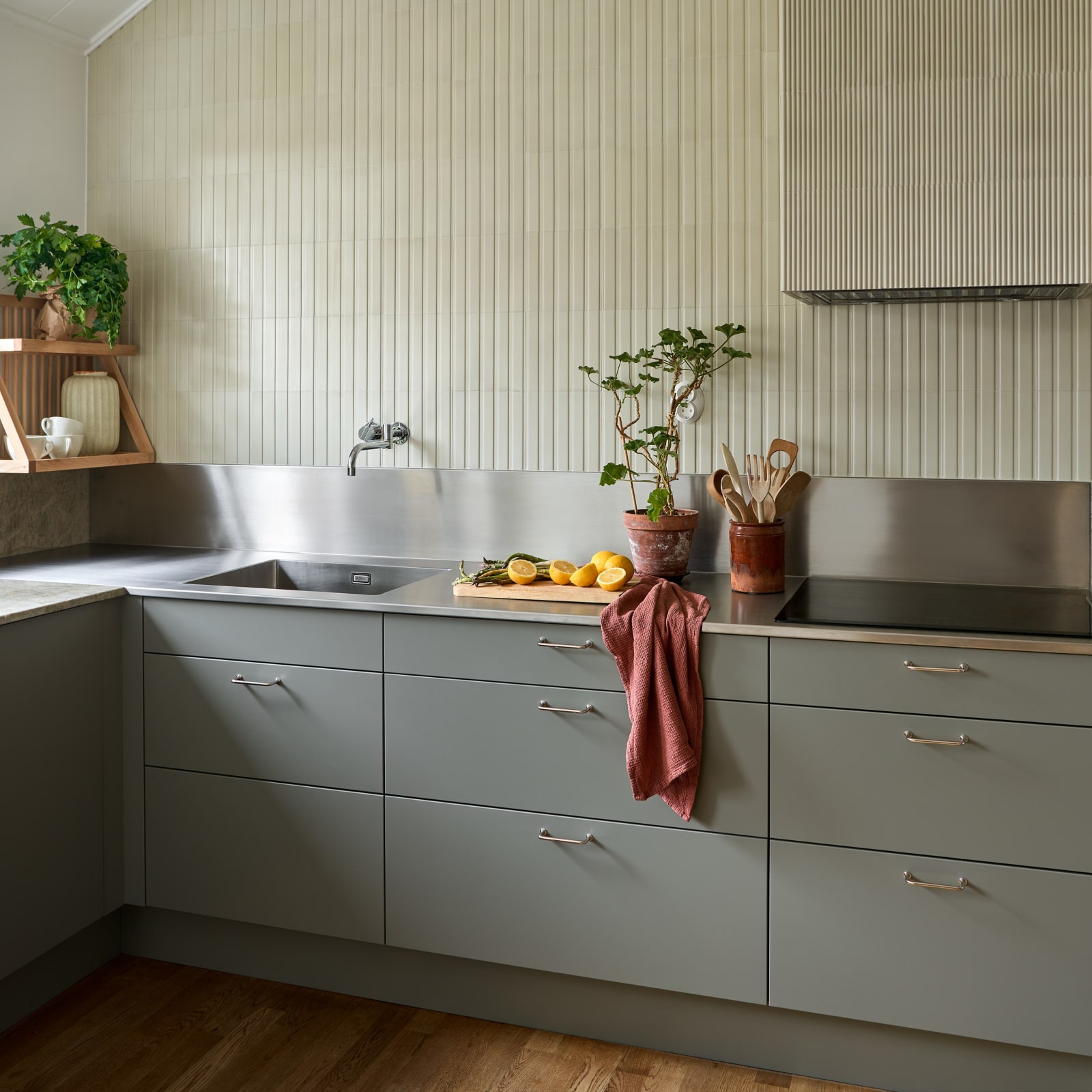 Lys grågrøn Athena Salvie køkken fra INVITA, håndtag och bordplade med splashback i rustfritt stål