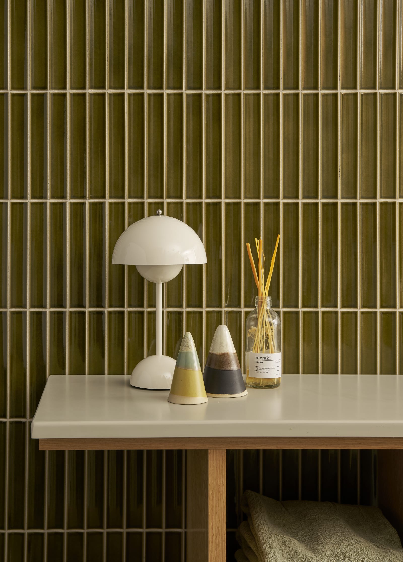 Nærbillede av eg hylder i Jubilæumsbad fra INVITA med grønne skaber inspireret av 1970'erne og grønne fliser