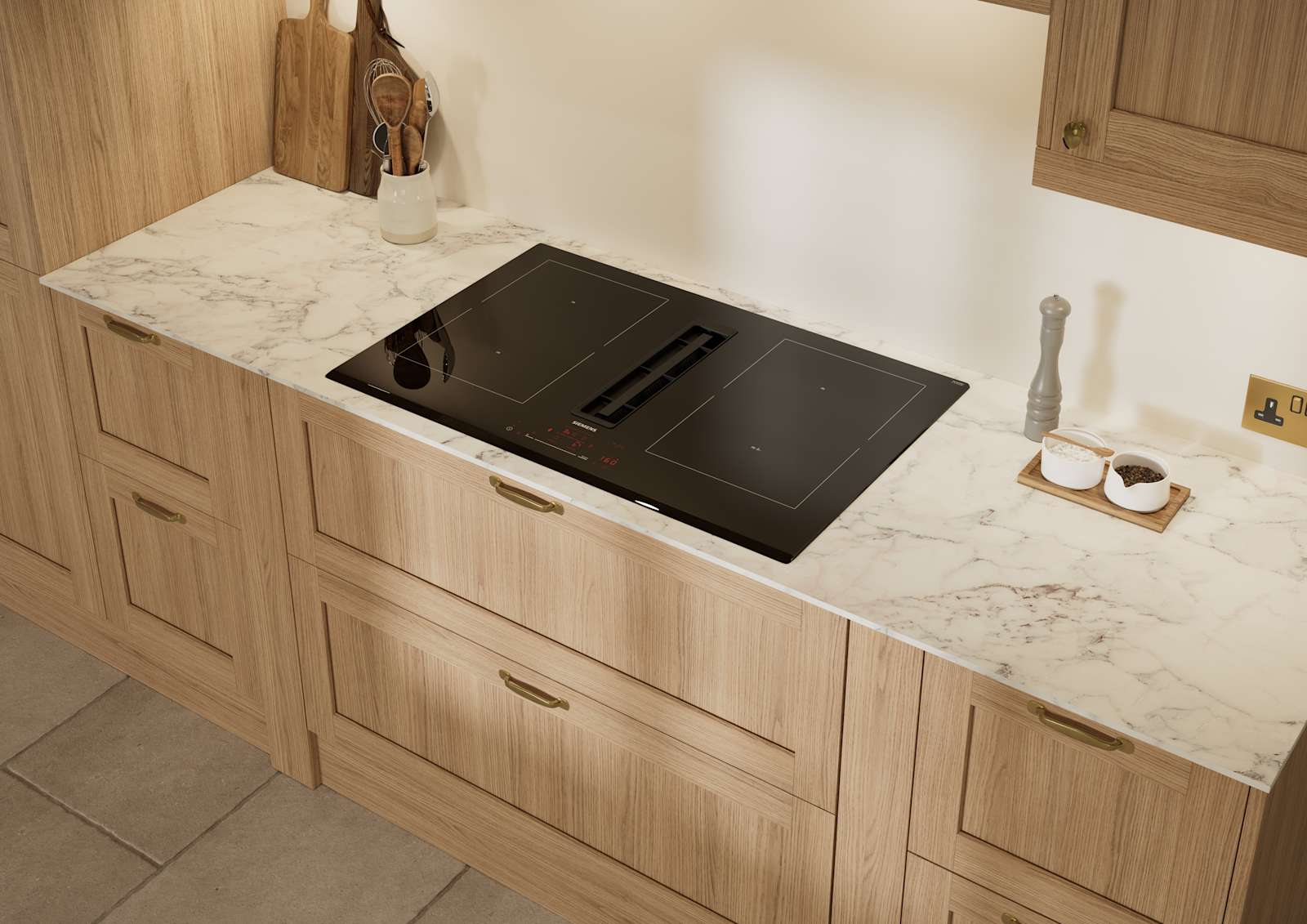 View of vented hob and marbled worktop in Traditional premium contemporary Shaker kitchen Ambleside in oak with brass knobs and handles.