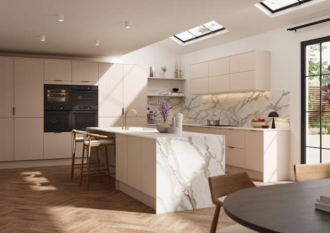 Fluted front kitchen Reed from Magnet in light warm neutral shade Shell, with a marbled splashback, worktop and decorative side on kitchen island with barstools and black handles, herringbone wood flooring.
