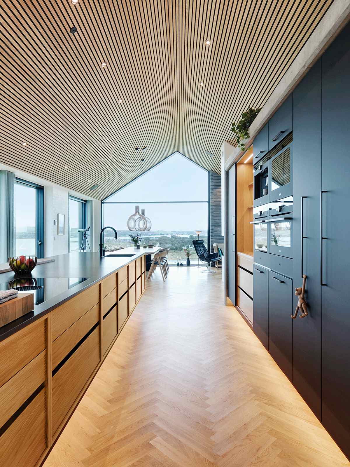Kitchen island in oak and tall cabinets in matt black laminate