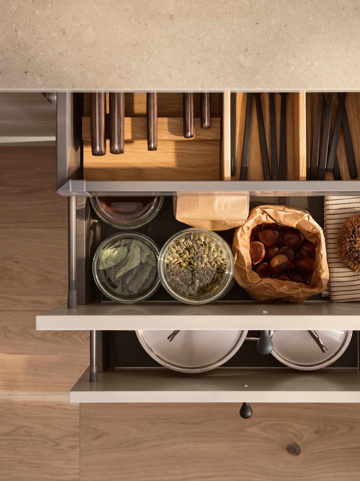 Bild ovanifrån av öppna köksskåp i beige köket Arkitekt plus gryning från Marbodal, med bestick- och redskapsinlägg i ek, glasburkar med torrvaror och tallrikar