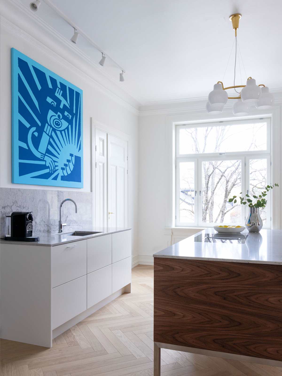 Kontrasterna skapar en harmonisk helhet där kökets moderna design står i naturlig dialog med bostadens historiska arkitektur.