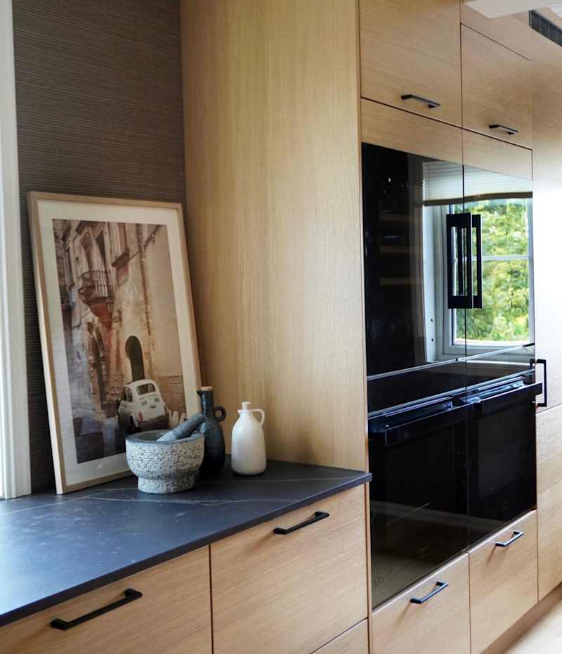Modern eikekjøkken Amfi Natur fra Sigdal med sort marmor Dekton benkeplate og sorte håndtag.