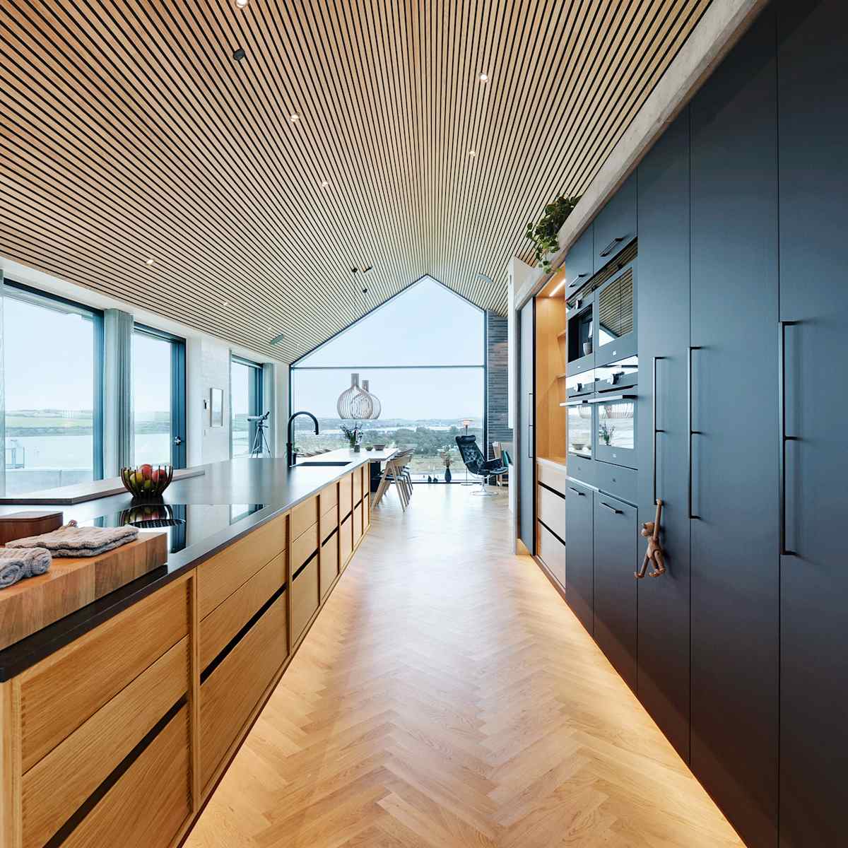 Kitchen island in oak and tall cabinets in matt black laminate