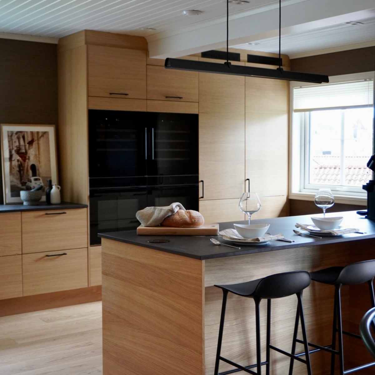 Modern eikekjøkken Amfi Natur fra Sigdal med sort marmor Dekton benkeplate og sorte håndtag.