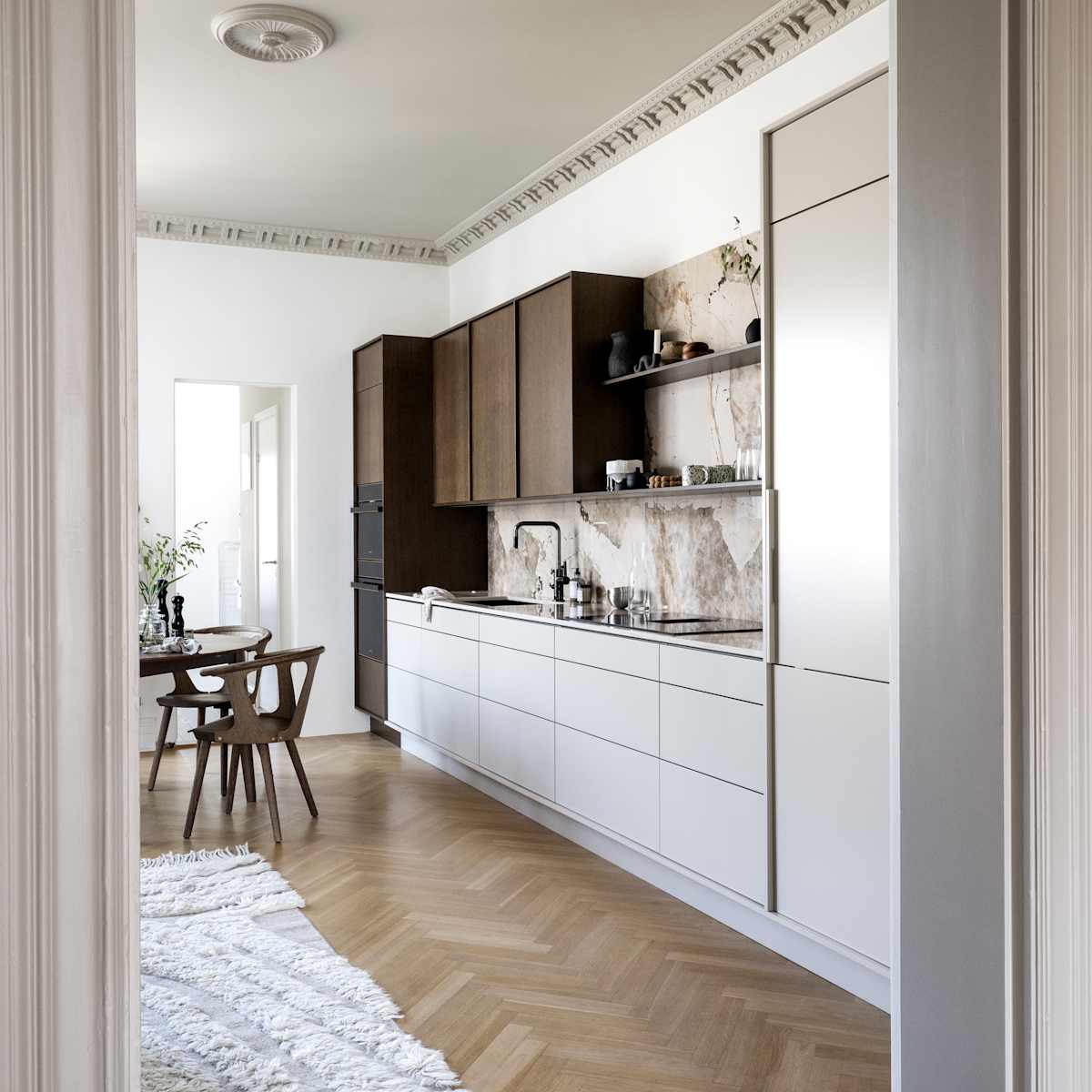 Kjøkken med kombinasjon av kjøkkenbenk i beige Line Korn med overskap i Favn finert eikedør i brunbeis fra Sigdal, benkeplate og sprutbak som matcher, og åpne vegghyller i brunbeiset eikefiner.