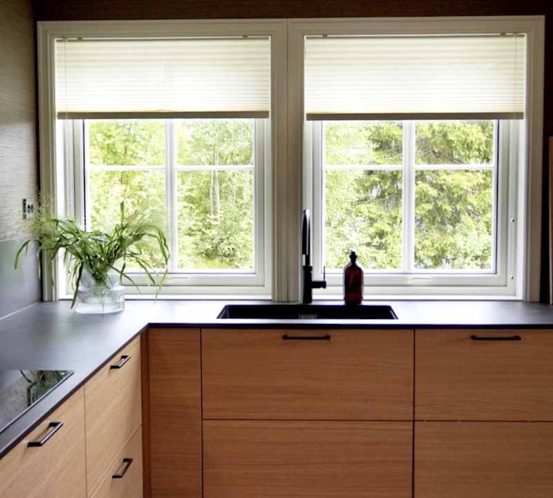 Modern eikekjøkken Amfi Natur fra Sigdal med sort marmor Dekton benkeplate og sorte håndtag.